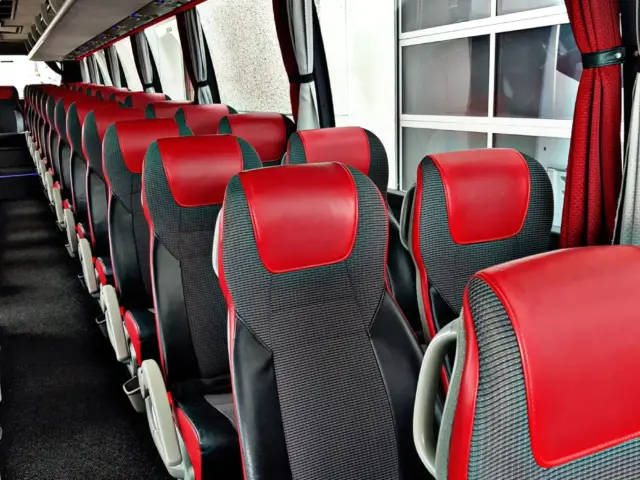 Auto nro 8: tilausajobussin sisätila, punamustat puolinahkaistuimet